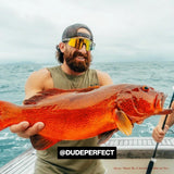 Dude perfect Tyler Nathan Toney Bearded fisherman proudly holding a bright orange speckled reef fish on a boat in the ocean with LosReyes shades on.