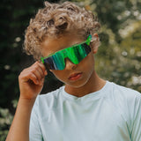Youth lifestyle image of LosReyes Prime Jurassic Pterodactyl sunglasses in vibrant green with a mirrored shield lens and wraparound frame, designed for active outdoor wear and high-performance UV protection.