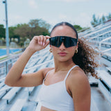 Female athlete wearing LosReyes Prime Polarized Black sunglasses with full-shield black lenses and performance frame, styled for running, sports training, and everyday UV protection in high-glare environments.