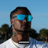 Front-facing lifestyle shot of Ross500 wearing LosReyes Elevate Blue Raz mirrored shield sunglasses with bold blue lenses and wraparound performance frame, styled for athletic and streetwear crossover