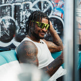 Ross500 wearing LosReyes Elevate Lime sport sunglasses with neon green lens and graffiti backdrop.