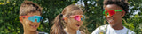 stylish kids laughing outdoors on playground, wearing uv protection colorful mirrored LosReyes sports premium glasses in red, green, and blue, showcasing cool youth active lifestyle eyewear shades