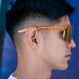 Lifestyle side profile of LosReyes Prime Galaxy Jupiter wraparound sports sunglasses in translucent orange, showing off premium gold mirrored lenses and secure-fit arm design.