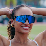 Lifestyle shot of LosReyes Prime Polarized Blue athletic sunglasses worn by a woman at the track, highlighting polarized mirror lenses for outdoor running and sports.