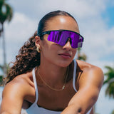 Lifestyle photo of woman wearing LosReyes Prime Polarized Purple sports sunglasses featuring mirrored wraparound lenses, black performance frame, UV400 protection, and athletic streetwear style