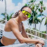 Lifestyle photo of woman wearing LosReyes Prime Polarized Yellow wraparound sports sunglasses featuring shield-style mirrored lenses, black high-performance frame, and UV400 protection for athletic outdoor training