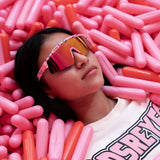Creative lifestyle photo of girl in pink ball pit wearing LosReyes Prime Youth Cream kids wraparound sunglasses with mirrored pink lenses and UV400 protection