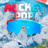 Promotional graphic of LosReyes Prime Youth Rocket Pop sunglasses featuring red, white, and blue frame with mirrored blue shield lens. Set on ice background to highlight summer cooling effect, youth athletic performance, and UV400 sports eyewear appeal.