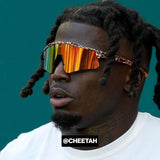 Side-angle lifestyle image of Tyreek Hill wearing LosReyes orange cheetah mirrored shield sports sunglasses with a wide lens wraparound design, styled for elite athletic performance