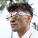 Person wearing reflective LosReyes lifestyle sunglasses with a blurred outdoor background