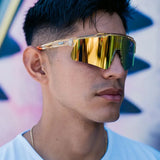 Front lifestyle view of LosReyes Prime Galaxy Sun wraparound yellow sports sunglasses with gold mirrored lens and amber speckled frame, modeled outdoors for versatile athletic use in sunlight.