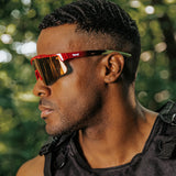 Side profile lifestyle photo of LosReyes Prime Jurassic T-Rex sunglasses in red and green with a mirrored shield lens and aerodynamic wraparound frame, designed for elite athletic performance, outdoor training, and full-spectrum UV protection.
