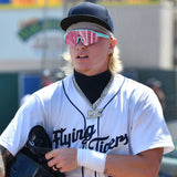 Max Clark standing on the field in a white Flying Tigers uniform, holding his helmet and wearing teal-rimmed LosReyes SHOWTIME shades during pregame activities