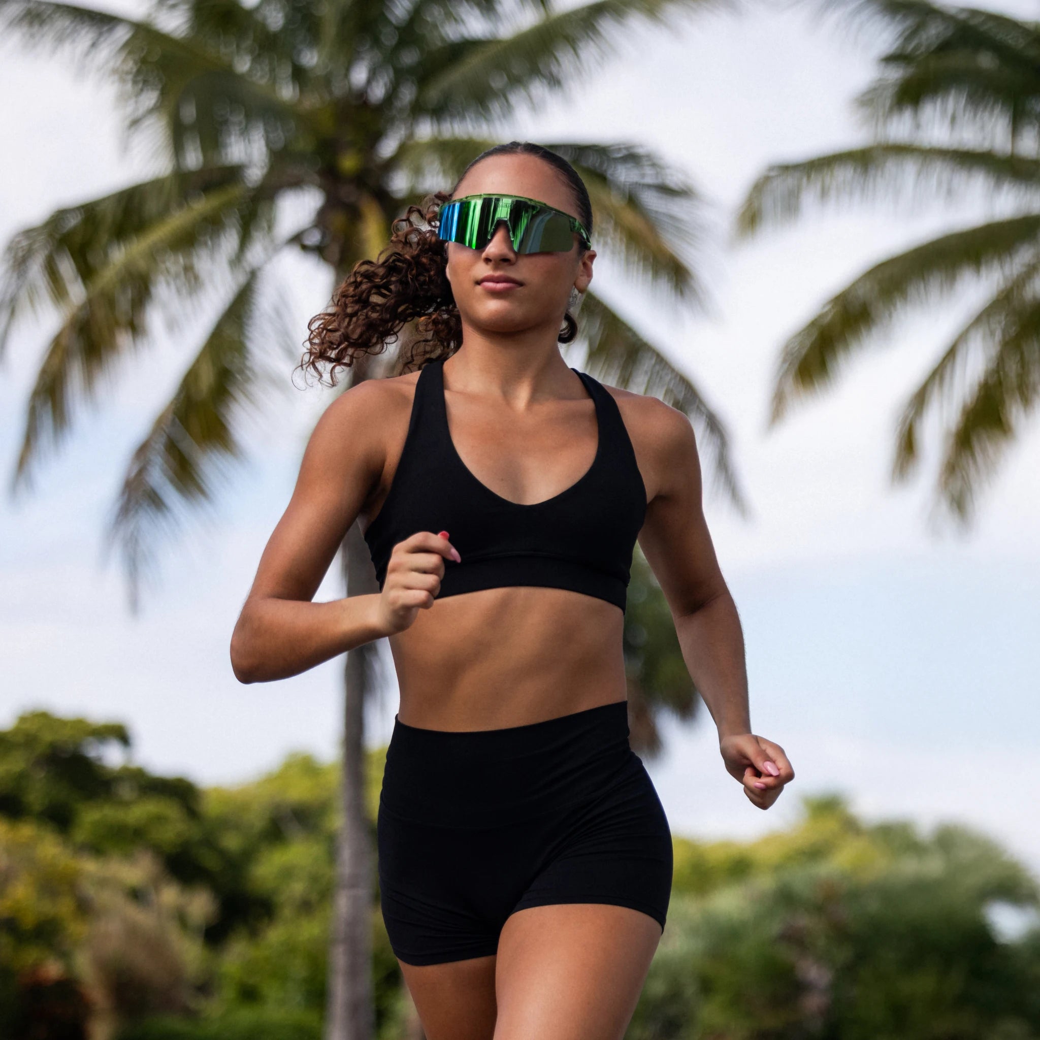 Athlete running outdoors wearing LosReyes Earth shades, featuring a mirrored blue lens and secure sport fit.