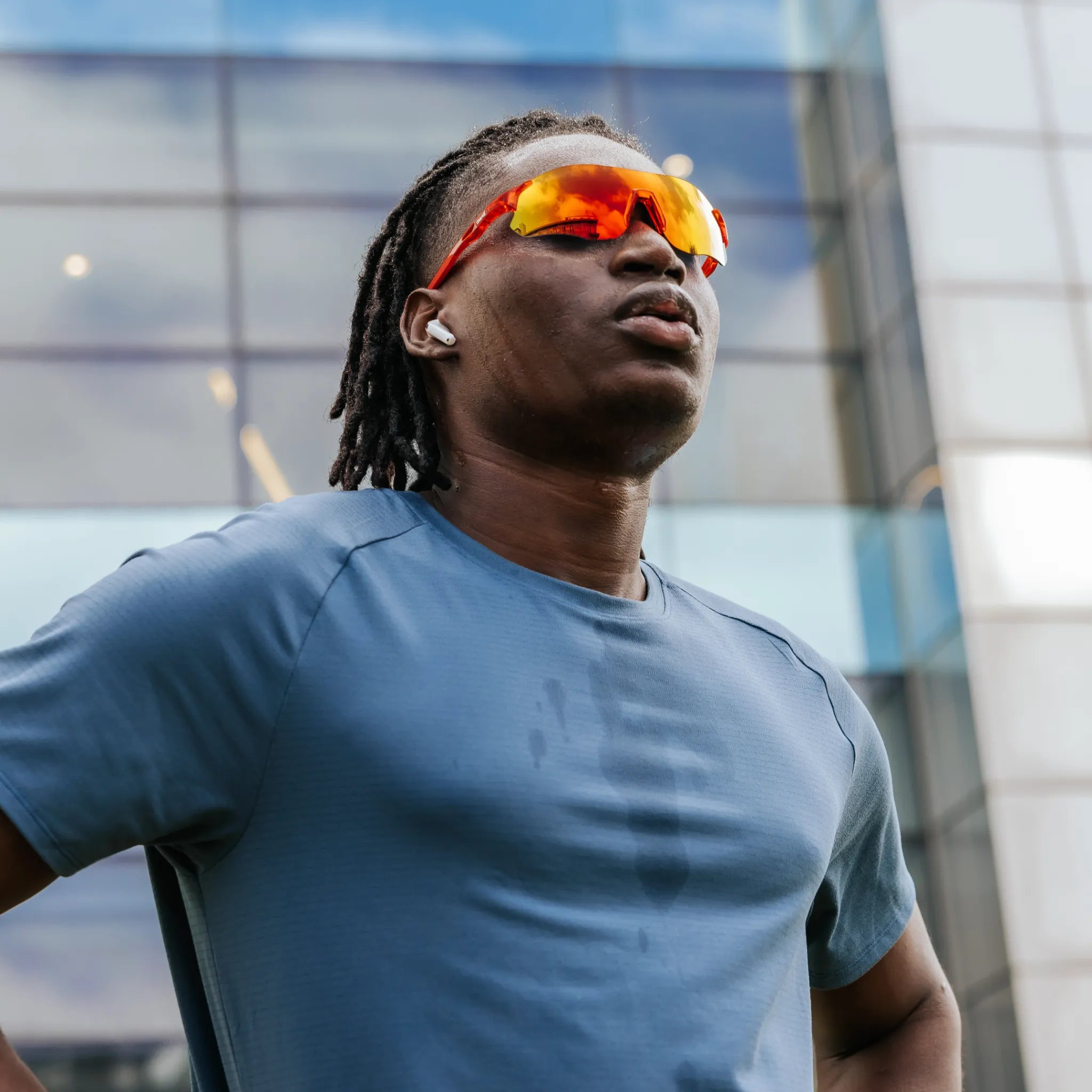Model wearing Edge Lava sunglasses during outdoor activity, featuring red-orange mirrored shield lenses.
