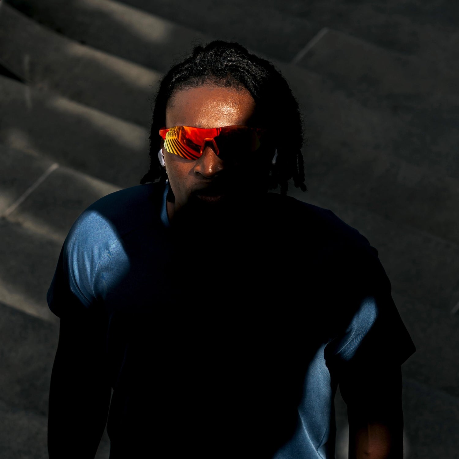 Top-down dramatic shot of model wearing Edge Lava sunglasses with red-orange mirrored shield lenses in low light.