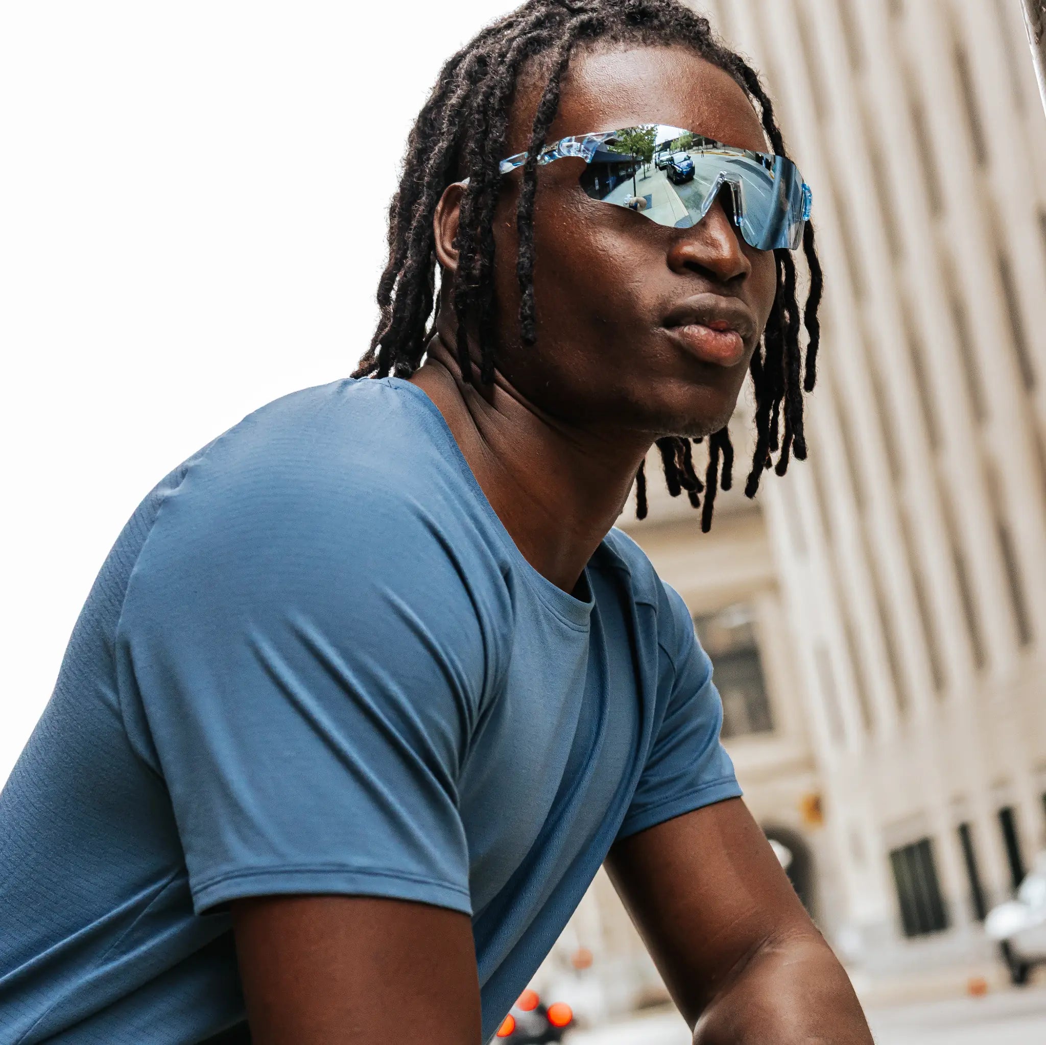 Model wearing Edge Ocean sunglasses in an urban setting, side profile view with mirrored blue lenses.