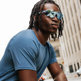 Model wearing Edge Ocean sunglasses in an urban setting, side profile view with mirrored blue lenses.