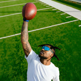 Ross500 wearing LosReyes Blue Raz sports sunglasses from the Elevate Collection while playing football, showcasing UV400 polarized protection and a $48 price point.
