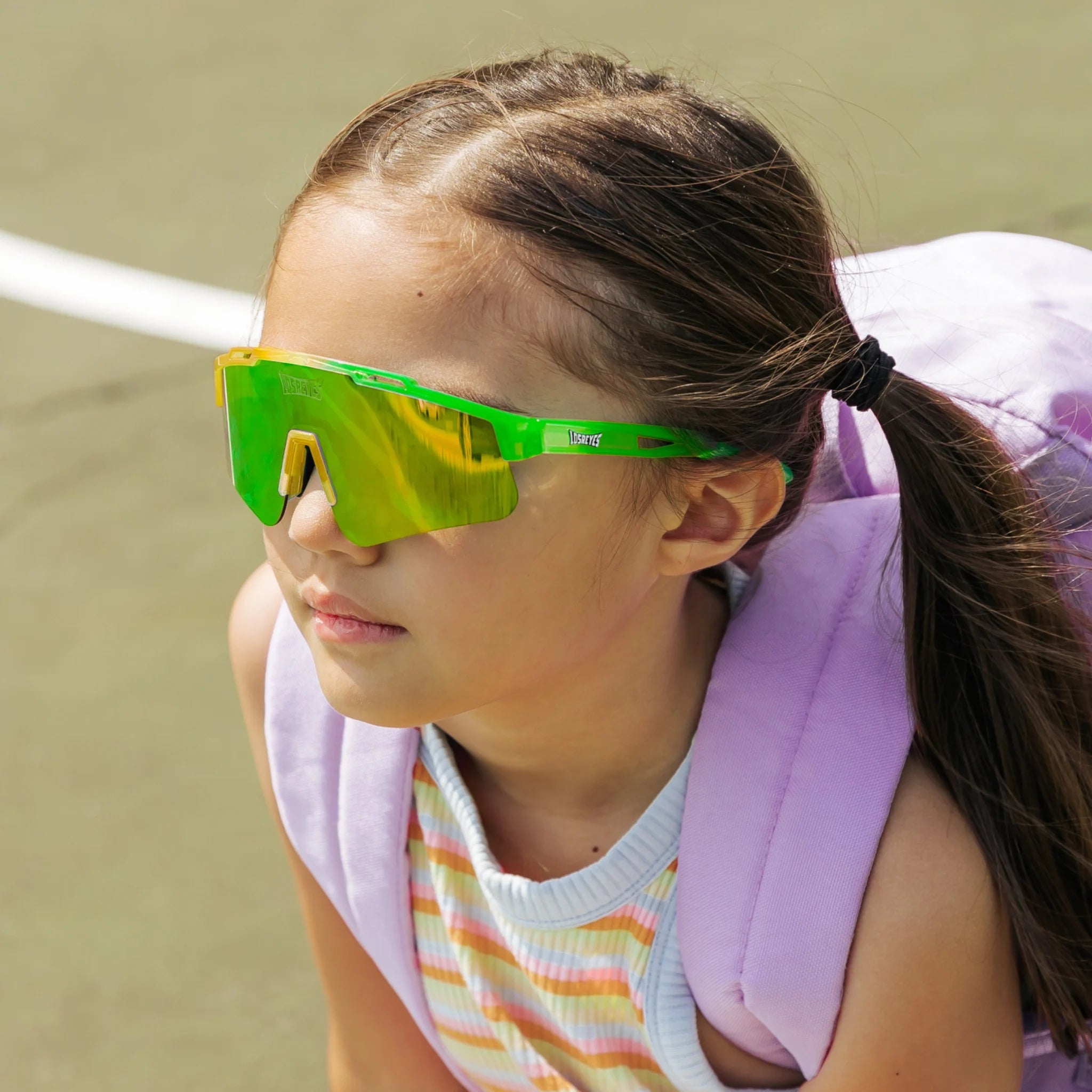 Kid in backpack wearing Candy Collection Banana green and yellow kids sport sunglasses outside