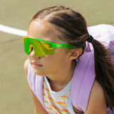 Kid in backpack wearing Candy Collection Banana green and yellow kids sport sunglasses outside