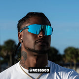 Front-facing lifestyle shot of Ross500 wearing LosReyes Elevate Blue Raz mirrored shield sunglasses with bold blue lenses and wraparound performance frame, styled for athletic and streetwear crossover
