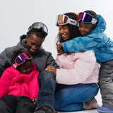 A family wearing LosReyes Everest snow goggles, with adults and kids enjoying winter gear together, showcasing helmet-compatible goggles with clear, fog-free lenses.