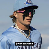 Close-up lifestyle photo of Max Clark wearing LosReyes pink wraparound shield sunglasses with mirrored lenses and a bold athletic design, styled for high-performance baseball and sportswear appeal