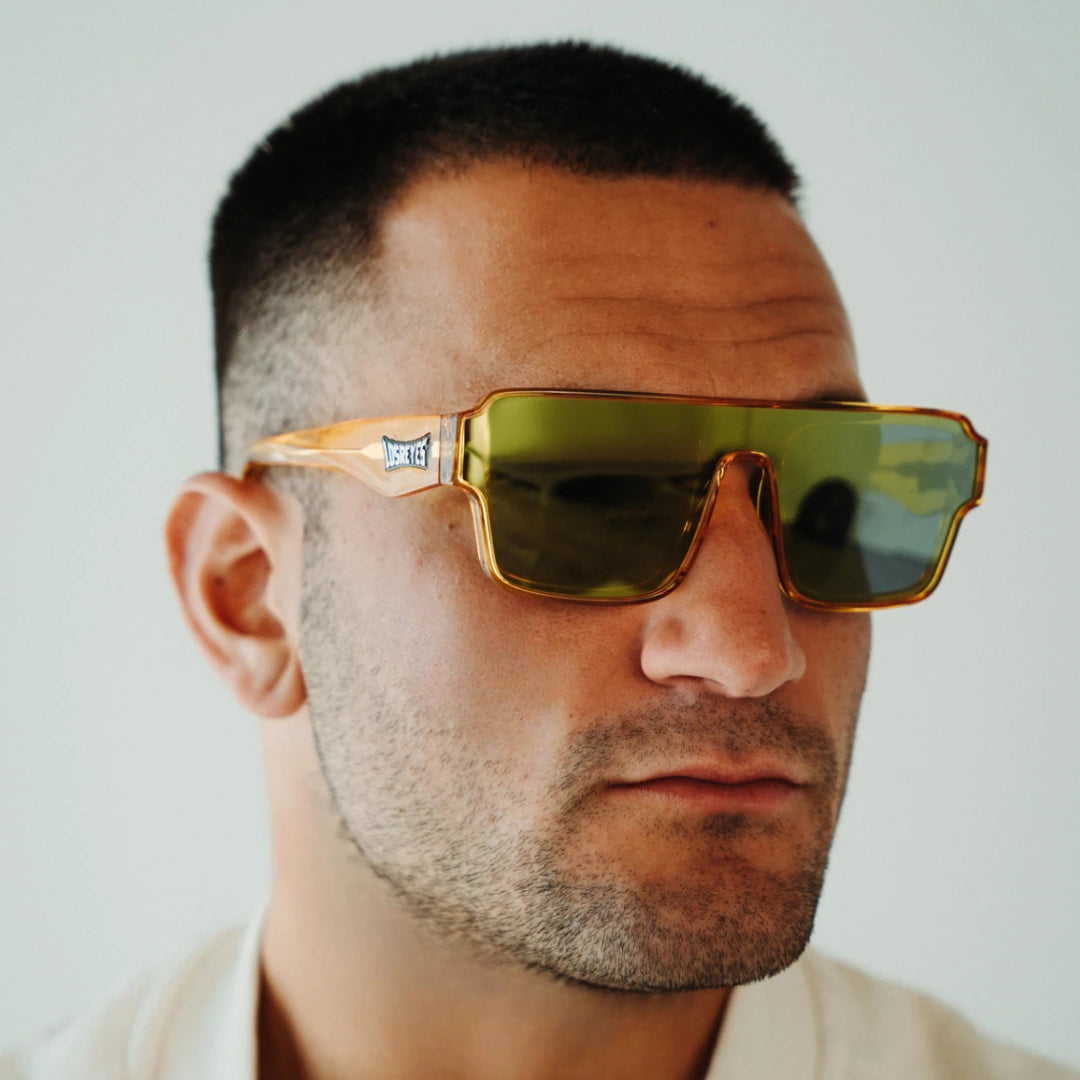 Lifestyle view of LosReyes Omega Apollon gold shield sunglasses featuring bold iridium mirror lenses, translucent amber frame, and wraparound UV400 performance design for elite training and high-impact style.