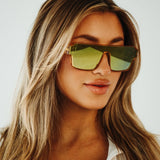 Lifestyle close-up of LosReyes Omega Apollon gold mirrored sports shield sunglasses featuring a bold wraparound lens, translucent amber frame, and high-performance UV400 protection for athletic fashion.