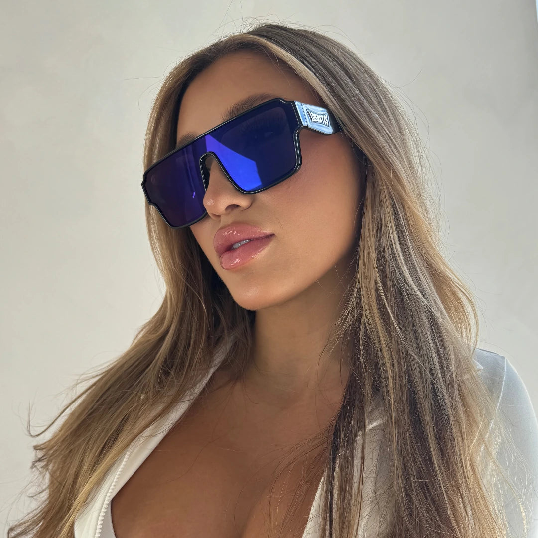 Lifestyle shot of LosReyes Omega Poseidon blue mirrored sports sunglasses with black wraparound shield frame, designed for UV400 protection and bold performance style.