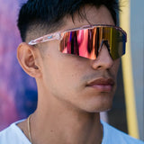 Model wearing LosReyes Prime Galaxy Venus wraparound sports sunglasses with pink mirrored shield lenses and clear frame, styled for athletic and casual wear.