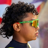 Side view of LosReyes Prime Youth Watermelon red mirrored sports sunglasses featuring UV400 protection, flexible arms, and a vibrant green speckled frame – worn by child for active lifestyle.