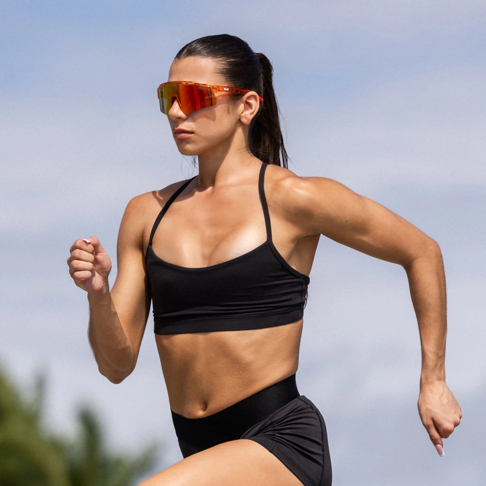 Female runner wearing LosReyes mars performance running sunglasses during a sprint workout outdoors.