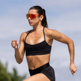 Female runner wearing LosReyes mars performance running sunglasses during a sprint workout outdoors.